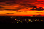 Auf dem Nachtpanorama ist die Wetterau zwischen Vogelsberg, Skyline der Metropole Frankfurt und dem Taunus, bei nächtlicher Beleuchtung und glutrotem Himmel dargestellt.